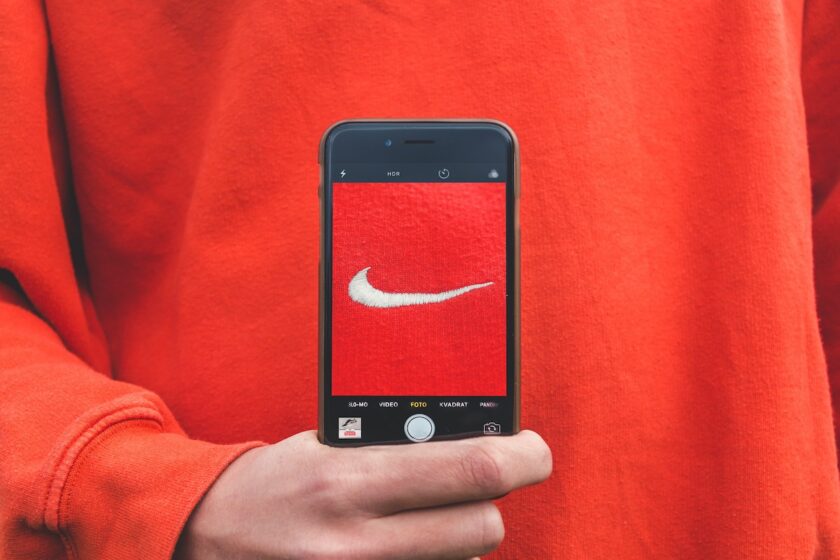Persona che fotografa etichetta Nike con iPhone, simbolo di notorietà e marketing del brand