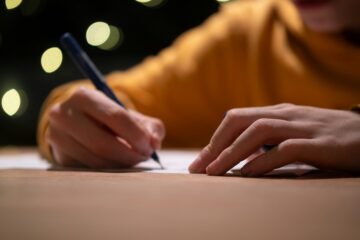 Uomo che scrive un assegno – gesto formale di compilazione a mano