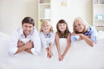 Famiglia sorridente sul divano simbolo di sicurezza economica